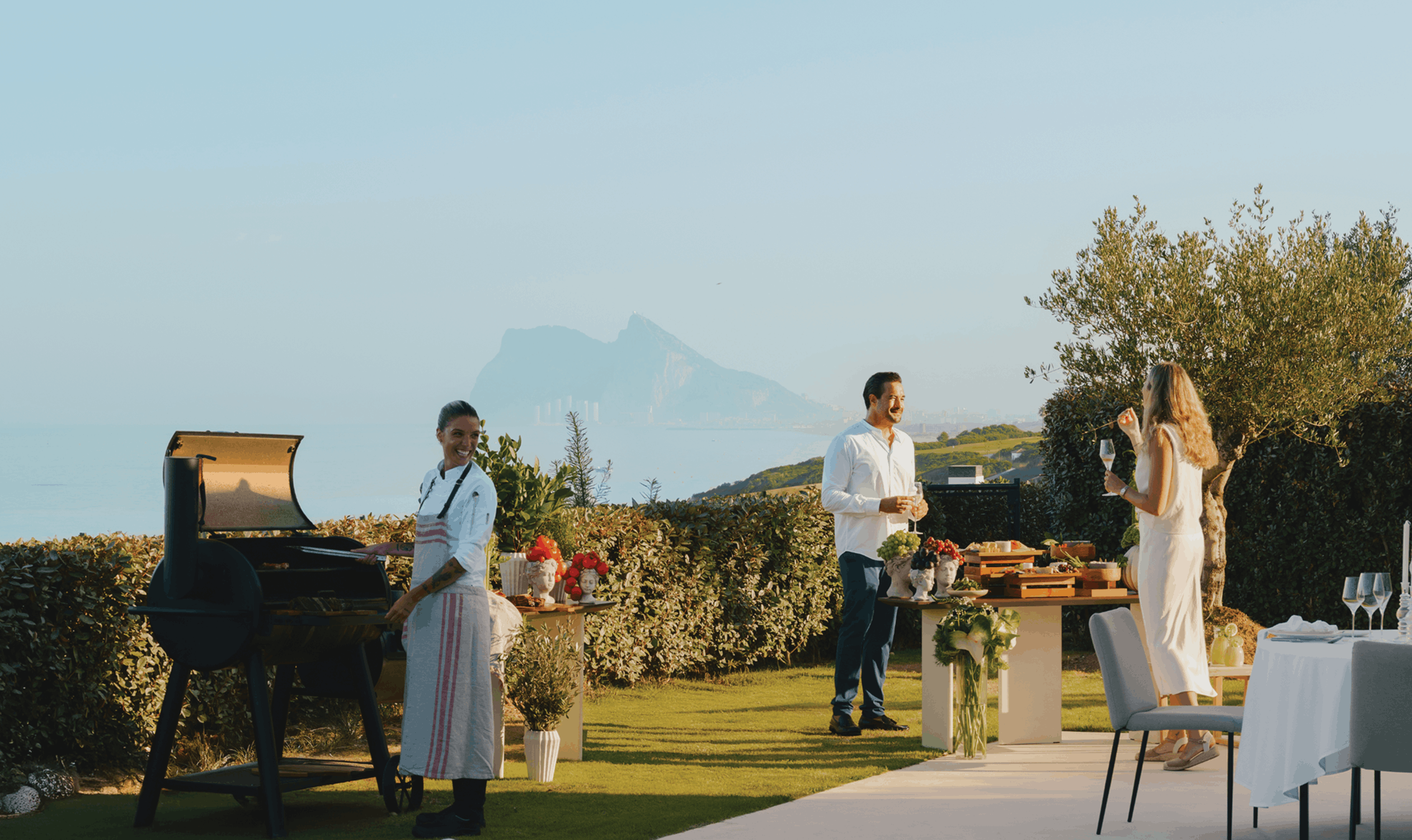 Residents enjoying an alfresco dinner with sea and Gibraltar views at a seafront luxury hotel-branded home in Spain